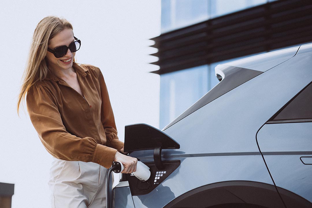 Woman puts charging cable into electric car