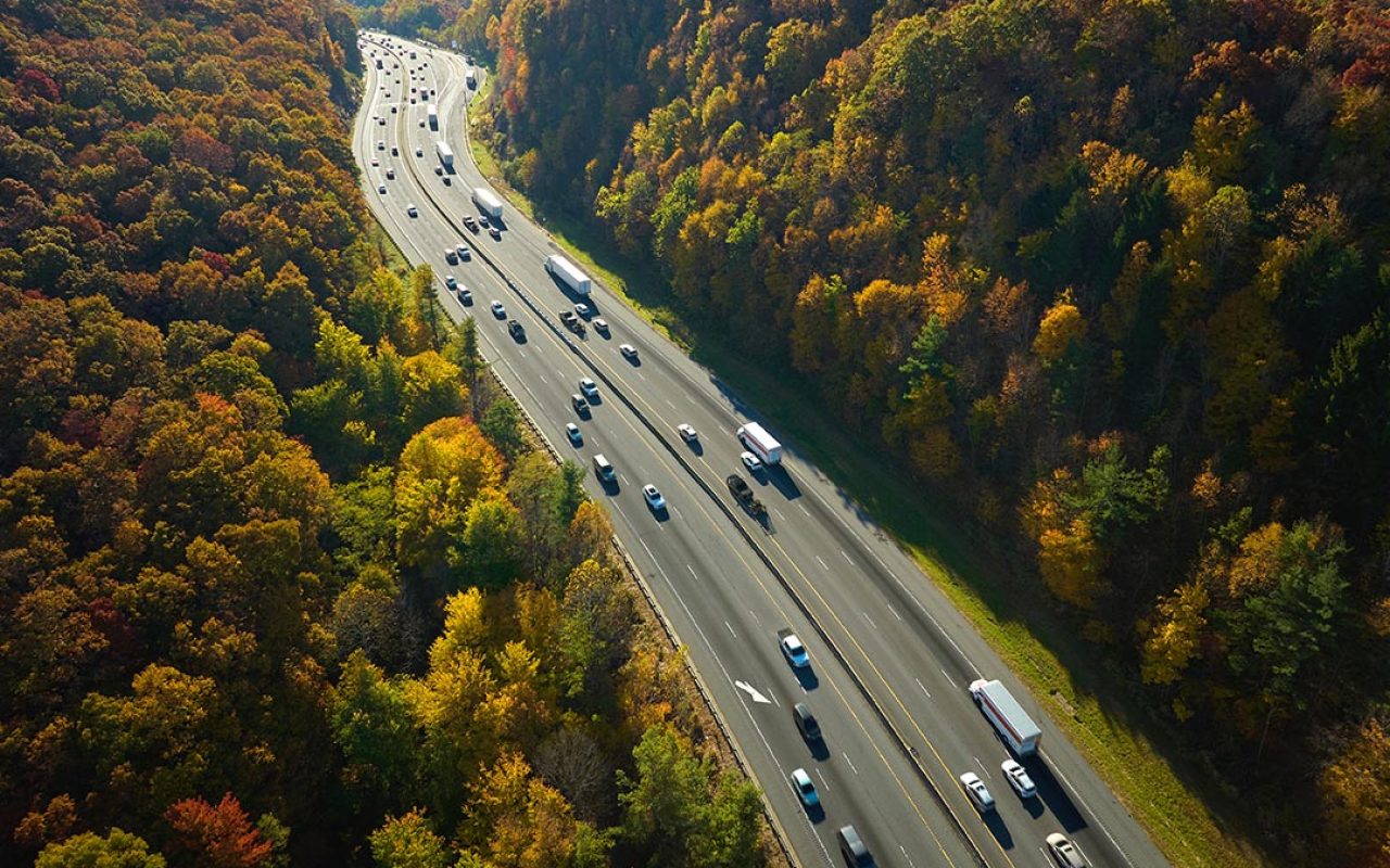 I-40 freeway in North Carolina leading to Asheville through Appalachian mountains in golden fall with fast moving trucks and cars. Interstate transportation concept.